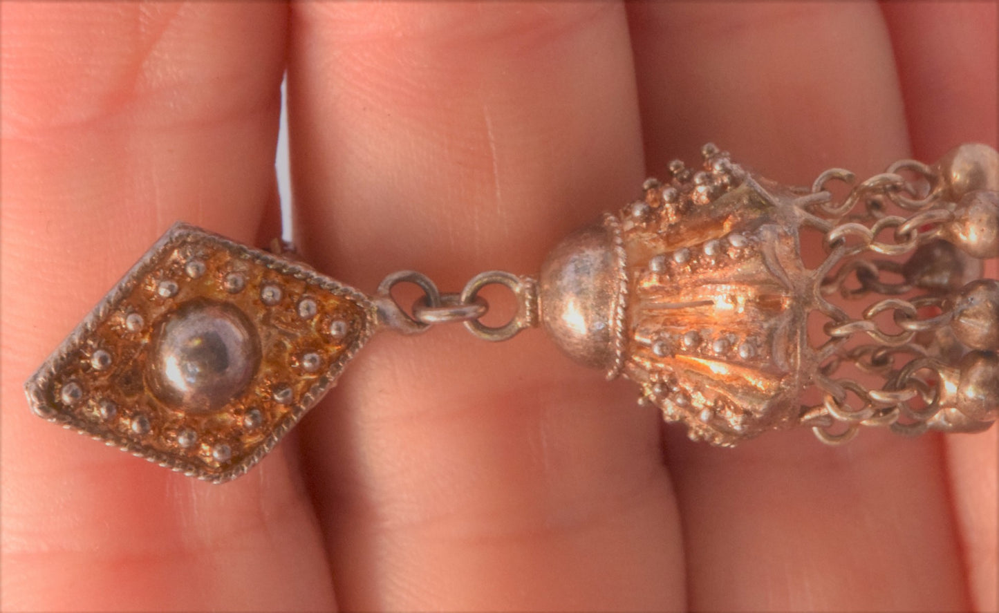 gold gilt dangle earrings on a hand