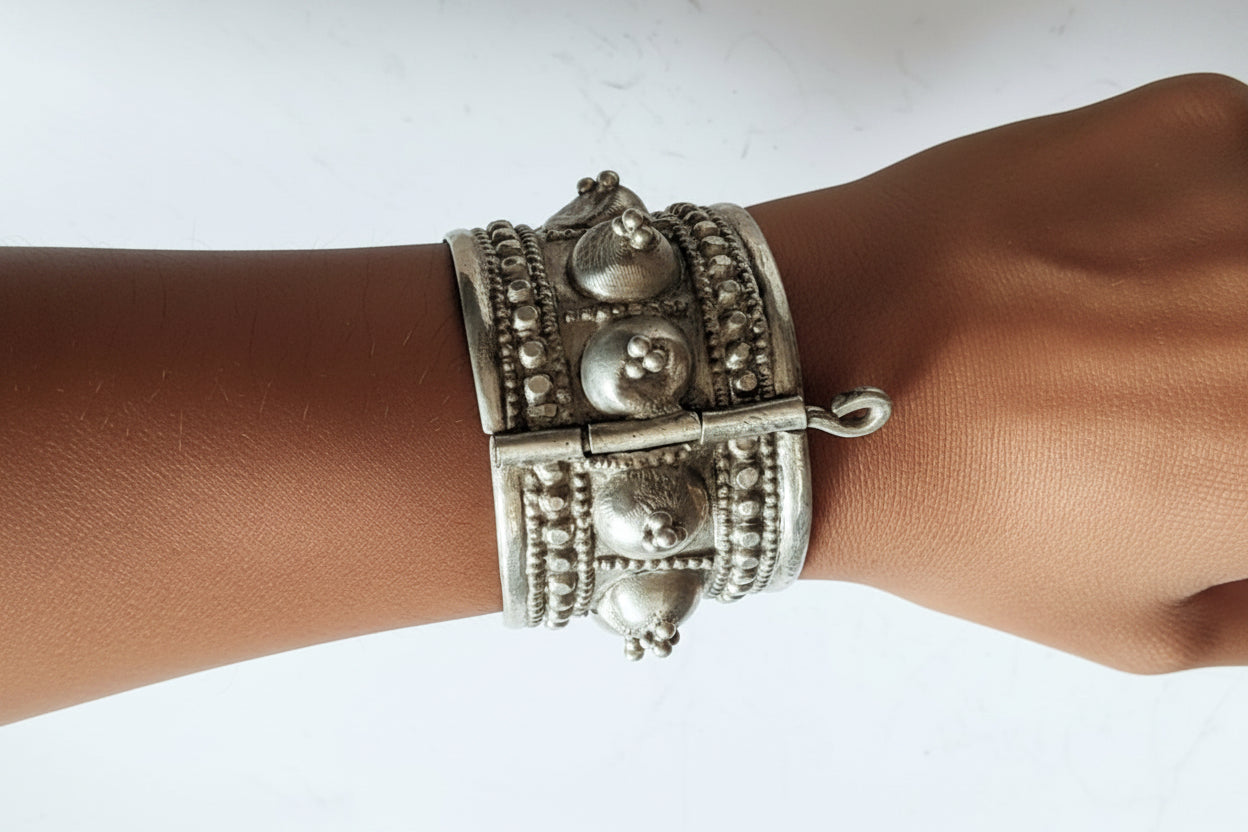 Silver bracelet with intricate designs on a wrist against a white background
