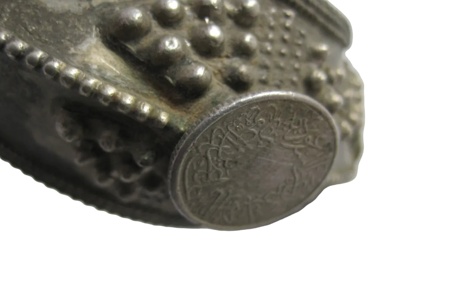 Close-up of a Saudi coin on a bracelet on a white background