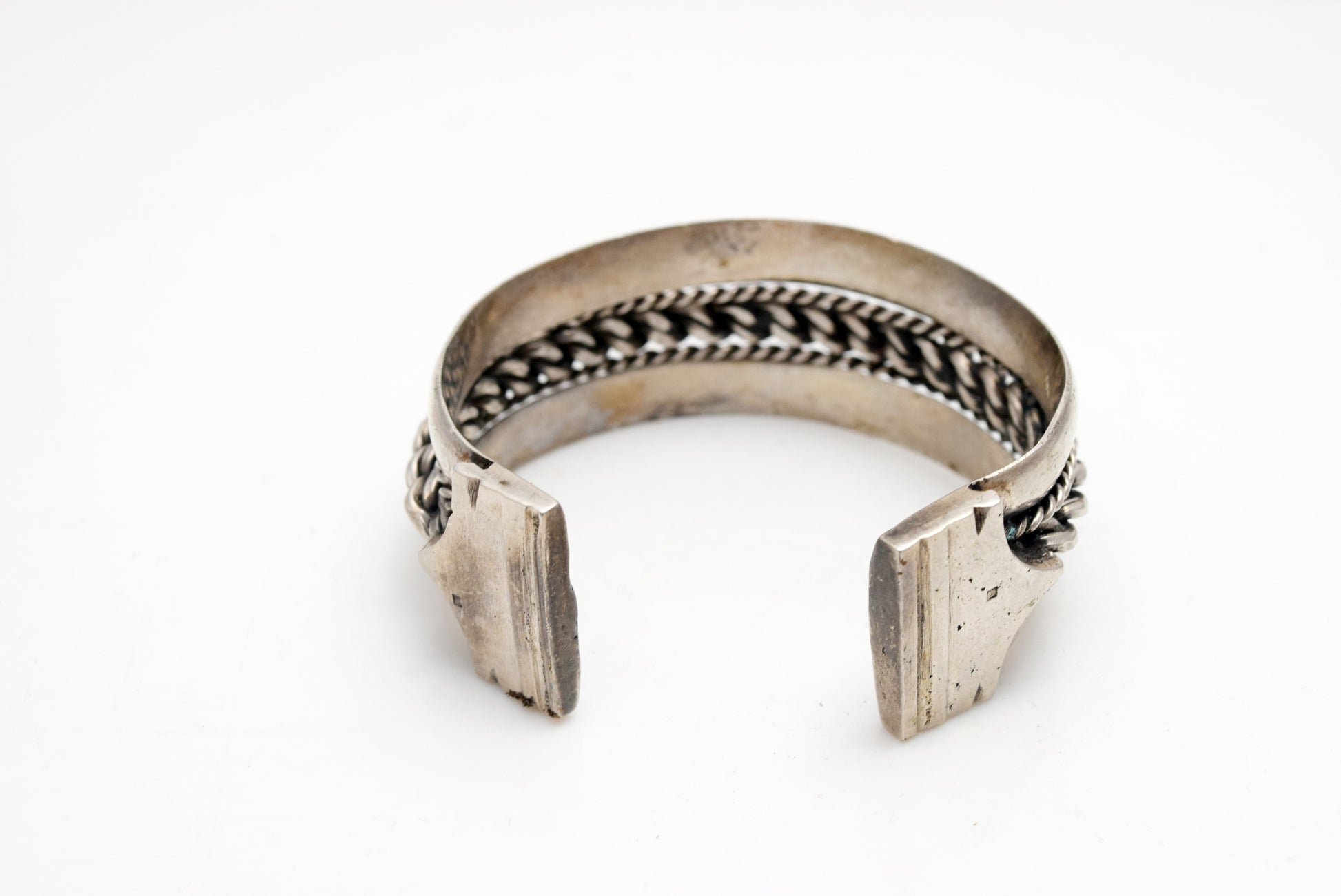 Silver bracelet with a braided middle on a white background