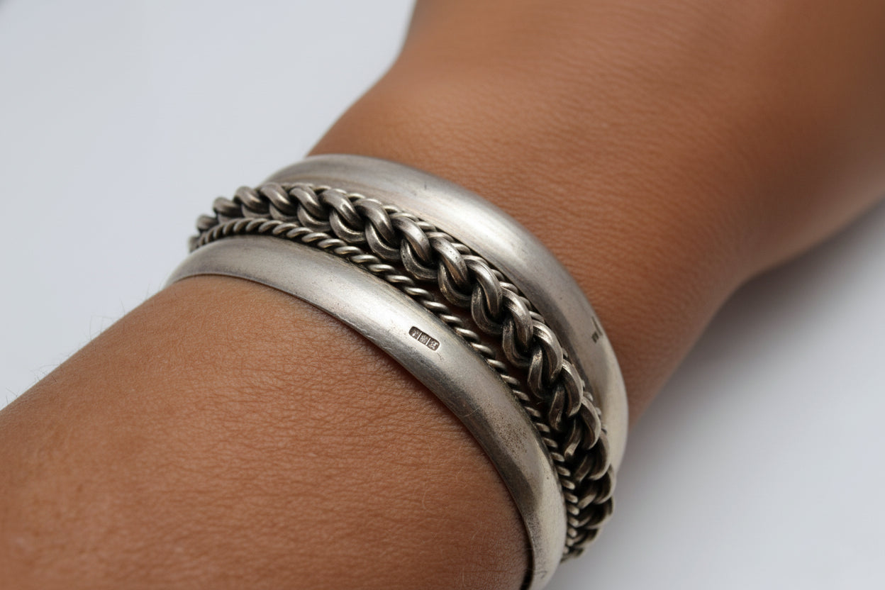 Silver bracelet with braided design on a wrist against a white background