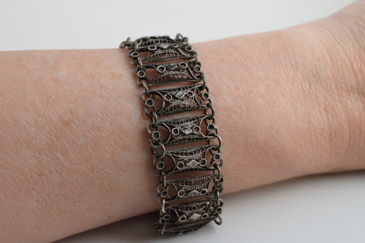 Decorative silver bracelet on a wrist against a white background