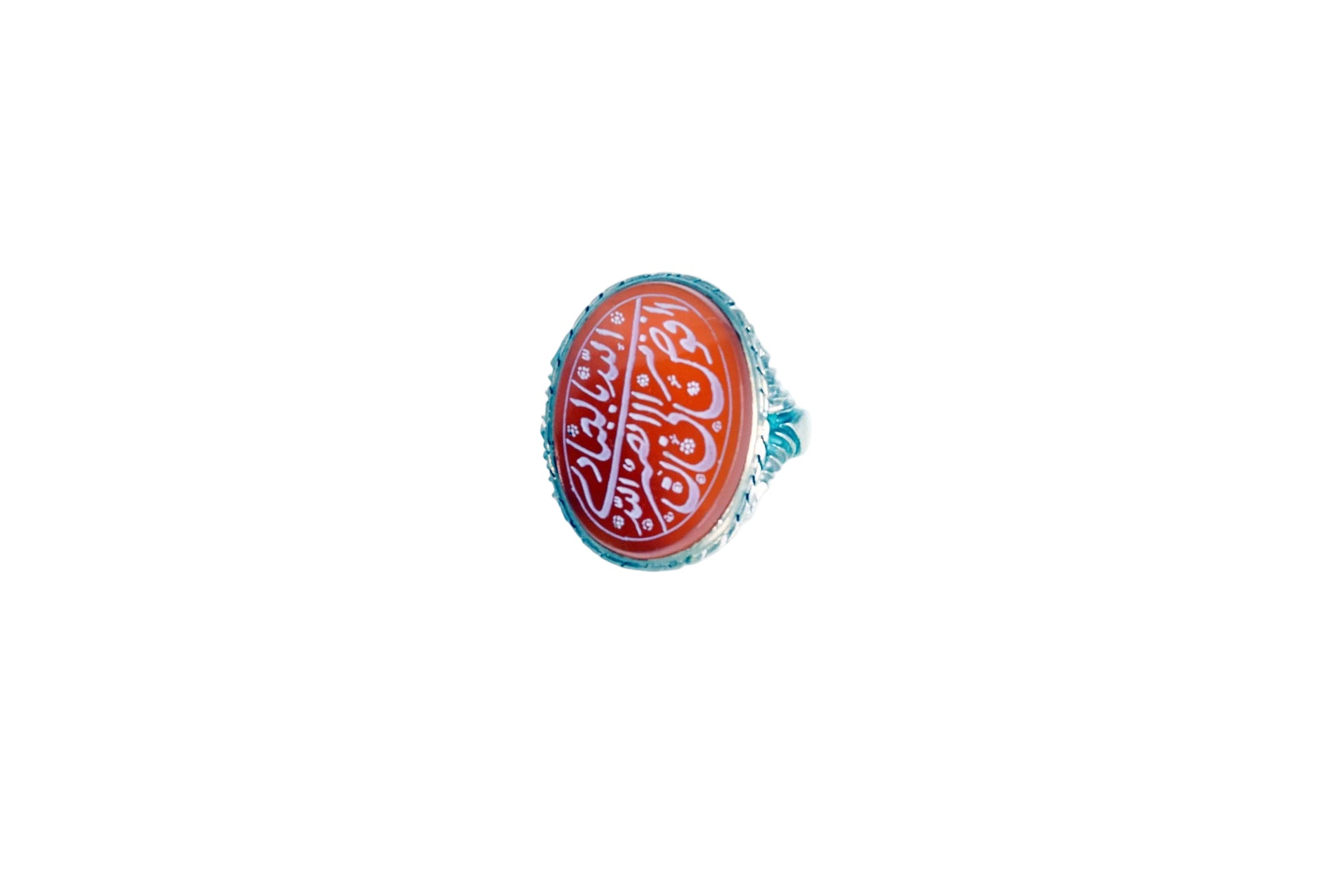 A silver ring featuring an oval red cabochon stone with white Arabic calligraphy, set against a plain white background.