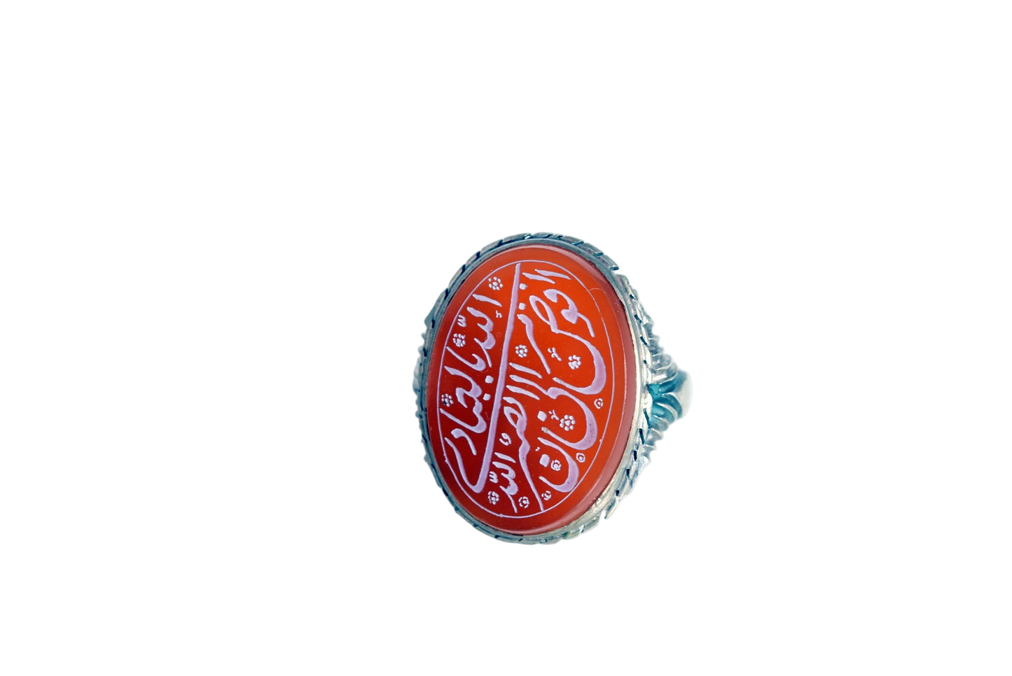 A silver ring featuring an oval red cabochon stone with white Arabic calligraphy, photographed on a plain white background.
