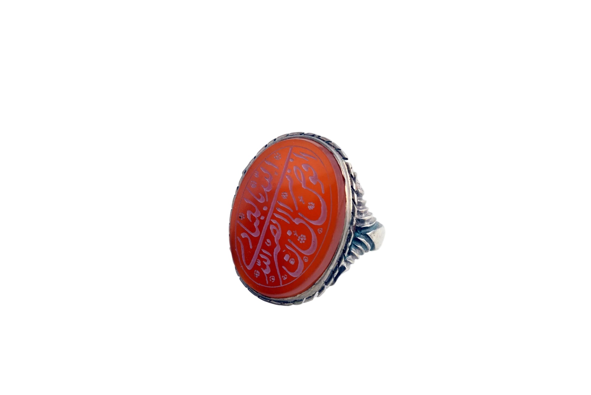 A silver ring featuring an oval red cabochon stone with white Arabic calligraphy, set against a plain white background.
