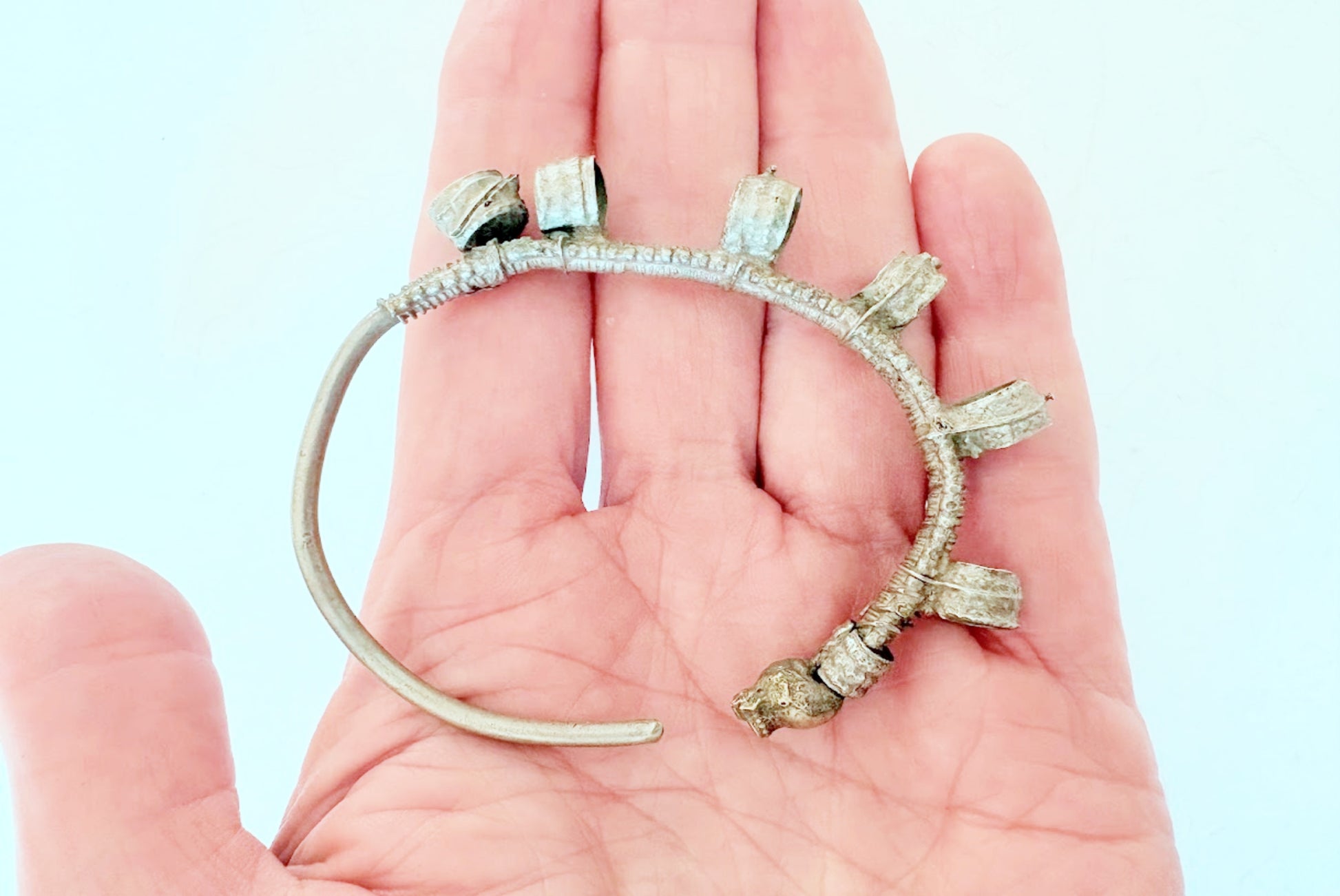 Hoop earring with loop elements held in a hand against a light blue background
