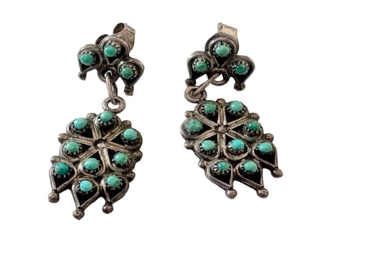 Pair of silver earrings with turquoise stones on a light background