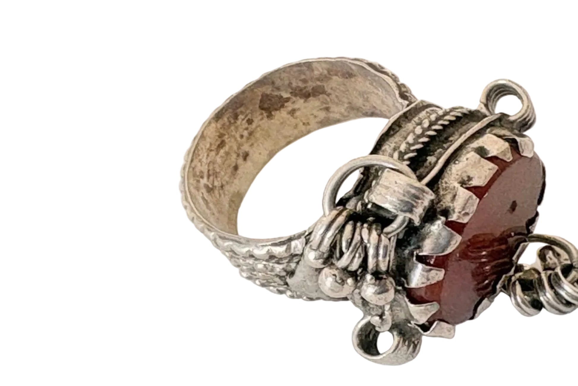 Silver ring with intricate designs and a red stone on a white background