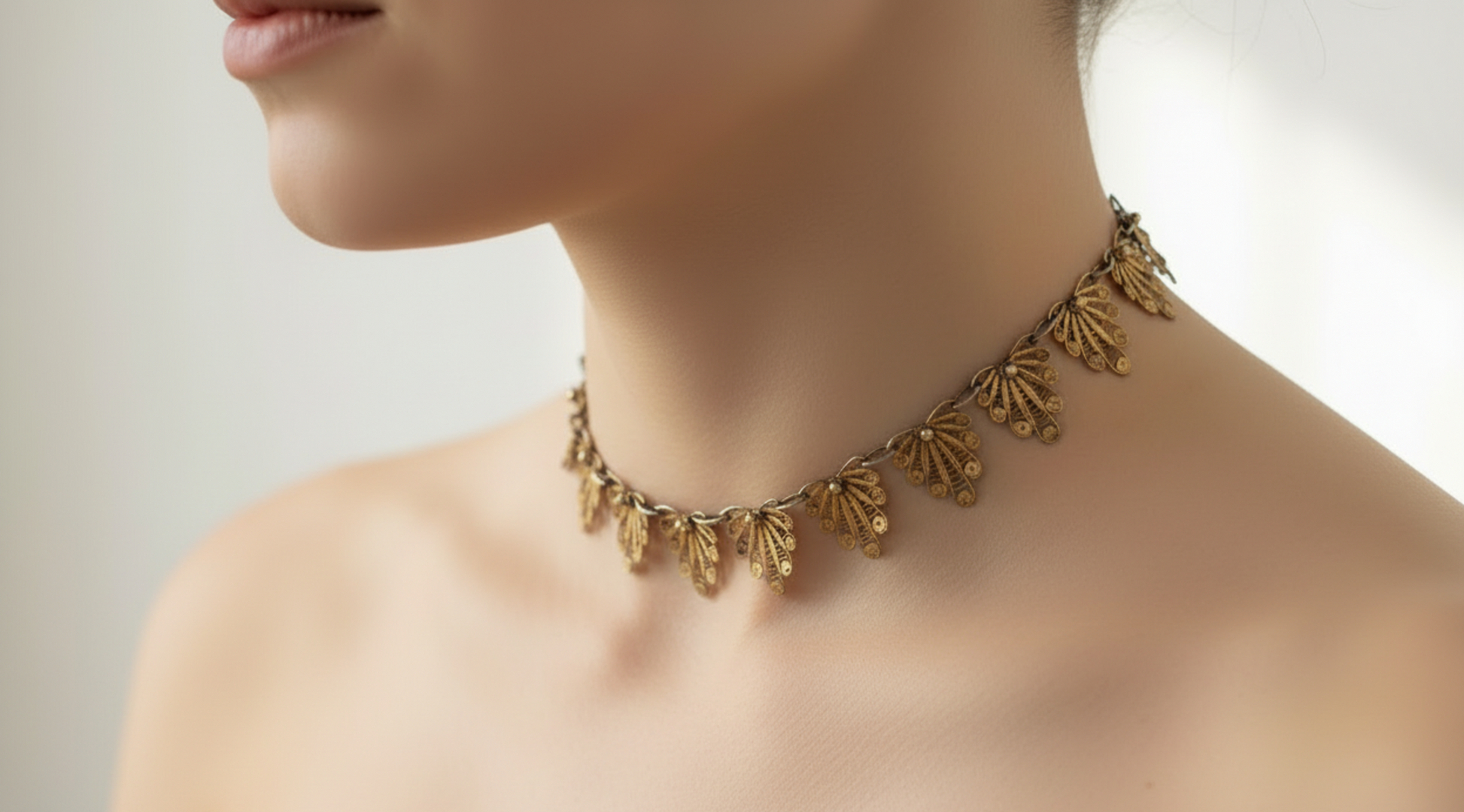 Gold gilt filigree necklace on a person against a neutral background