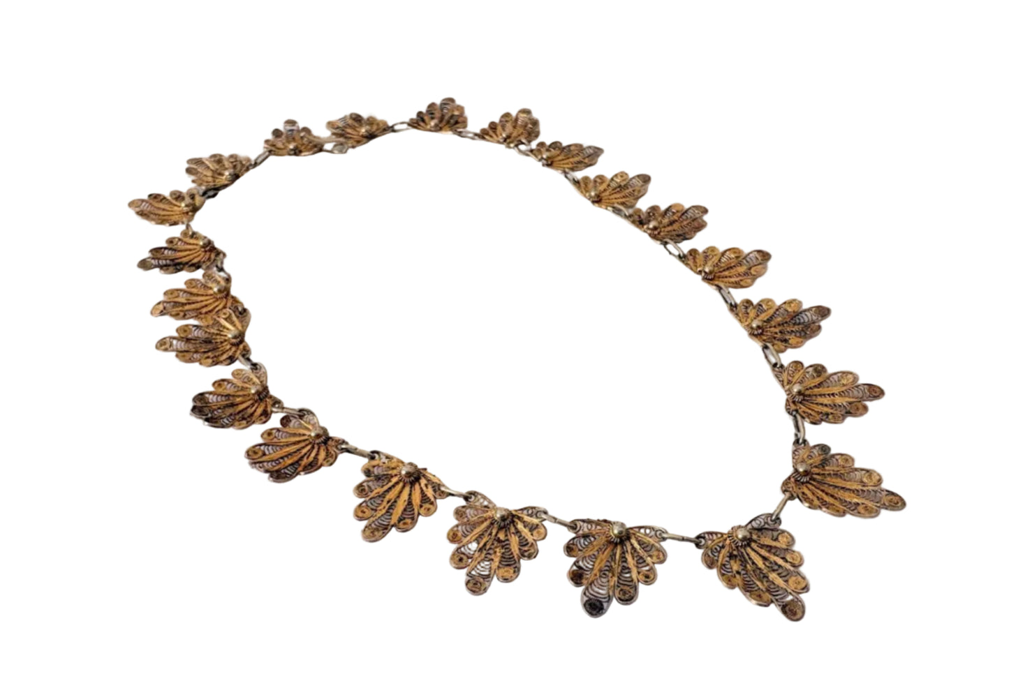 Decorative gold colored filigree necklace on a white background