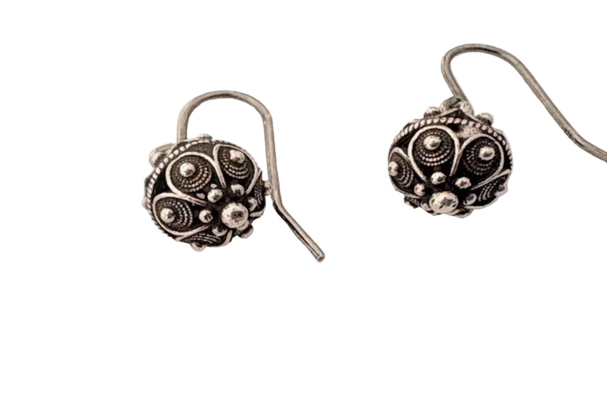 Pair of silver earrings with intricate designs on a light background