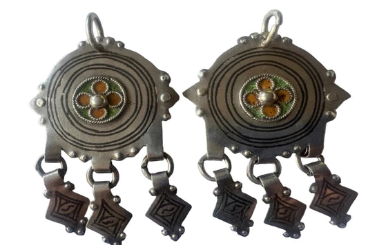 Pair of silver pendants with intricate designs on a white background