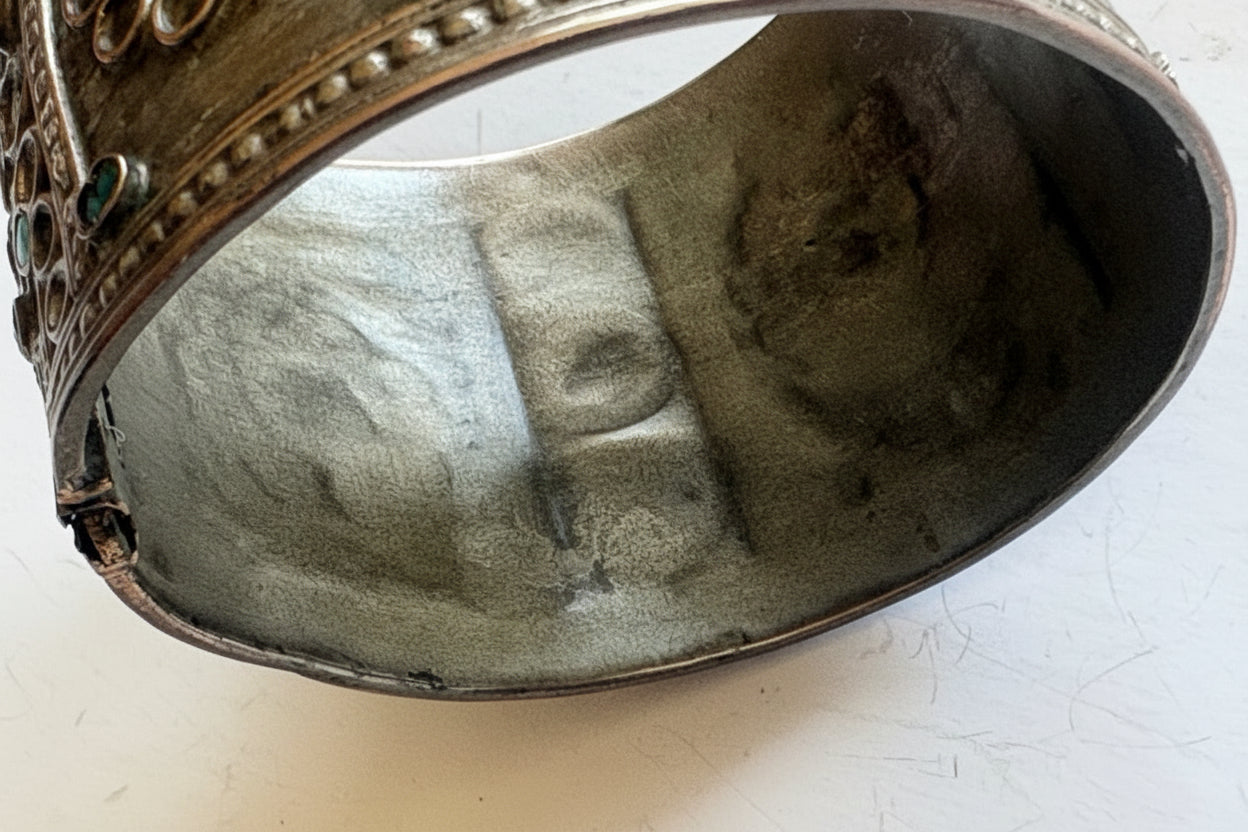 Close-up of the inside of a silver bracelet on a white background