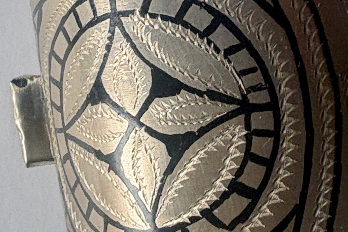 Close-up of a flared bracelet with intricate patterns on a white background