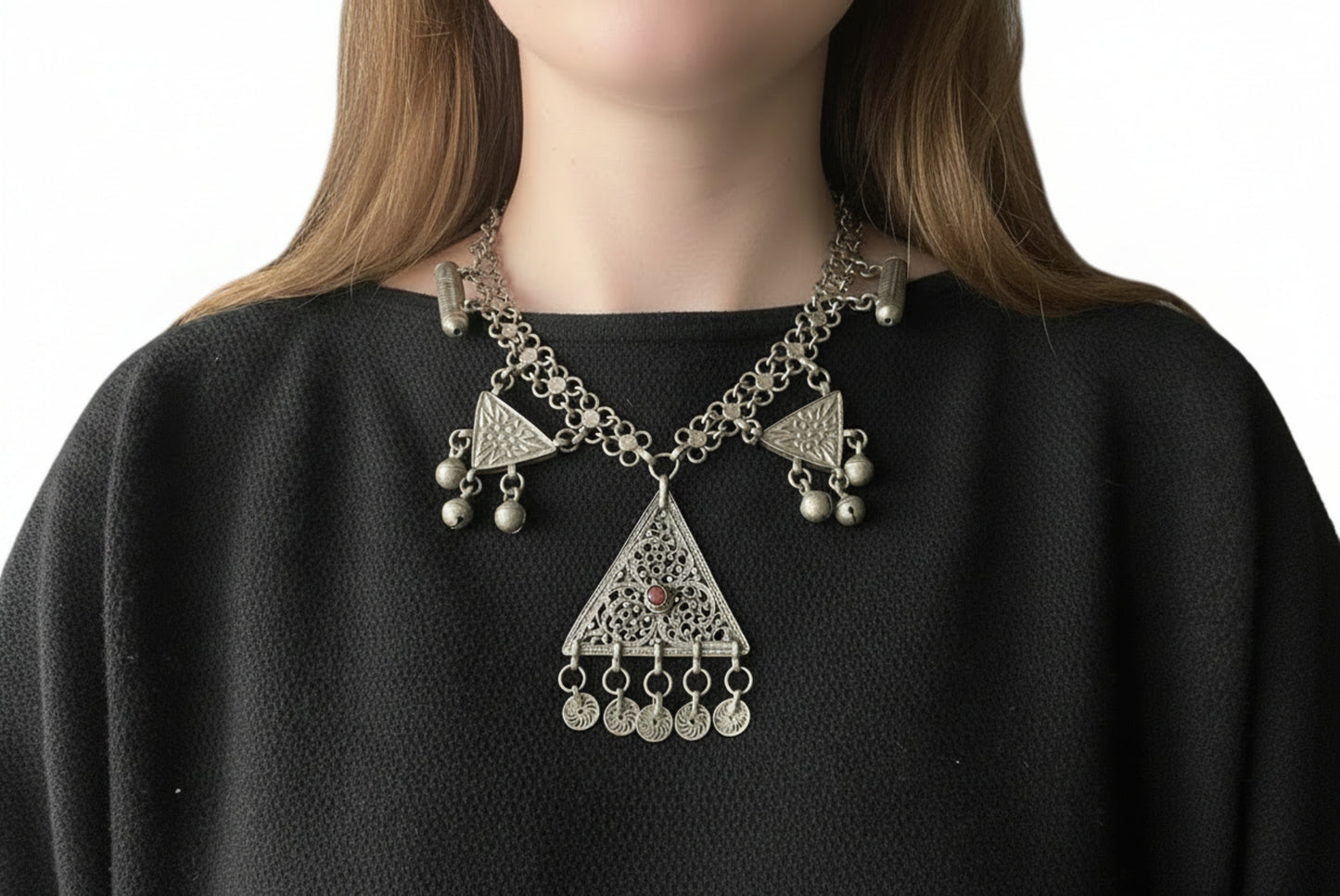 Person wearing a silver necklace with triangular pendants 