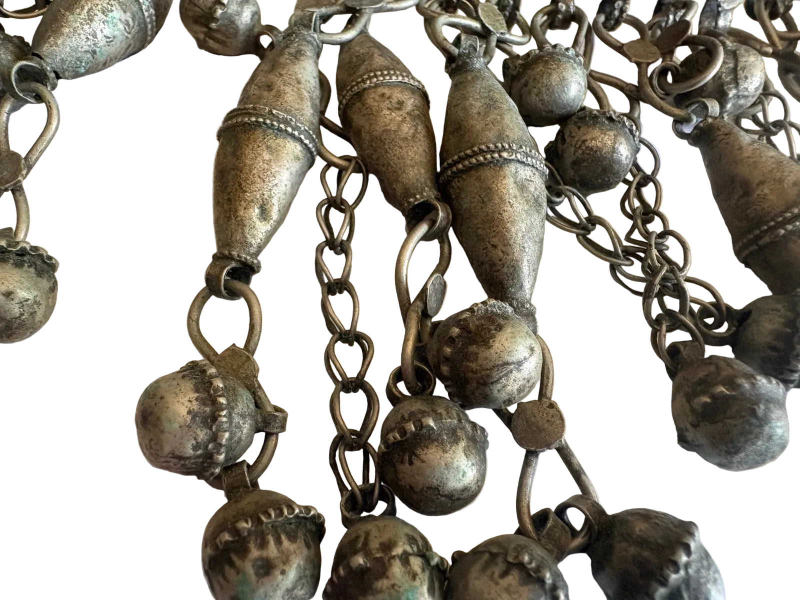 Close-up of a silver torc necklace with spherical pendants on a light background