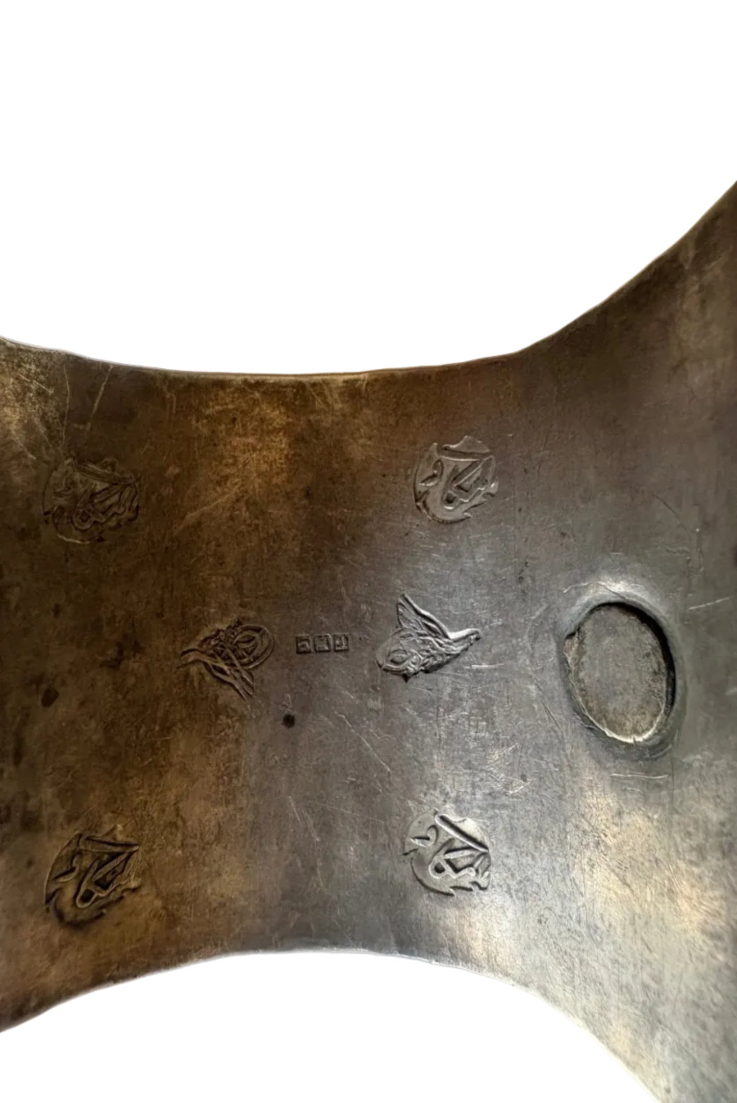 Close-up of three-part Egyptian hallmark on a silver bracelet on a white background