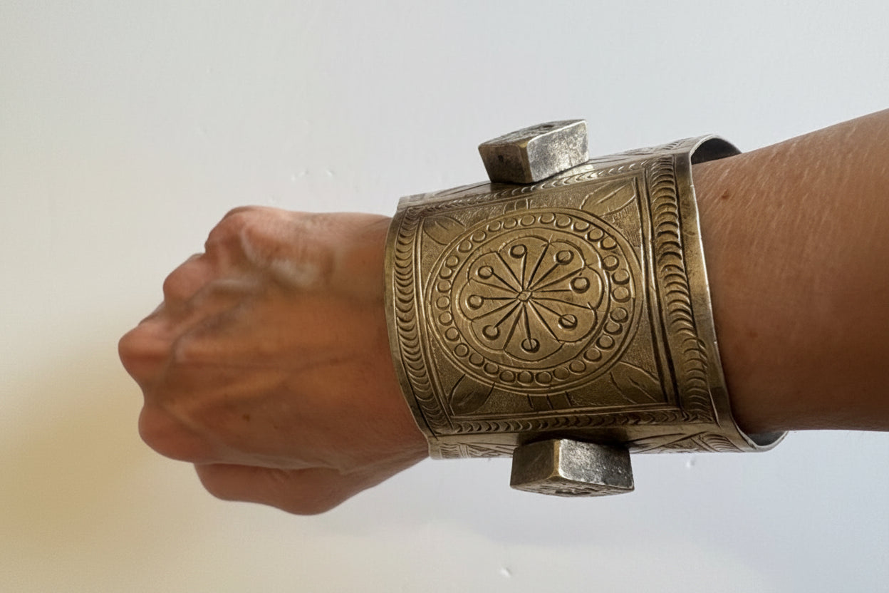 Decorative silver bracelet on a wrist against a white background