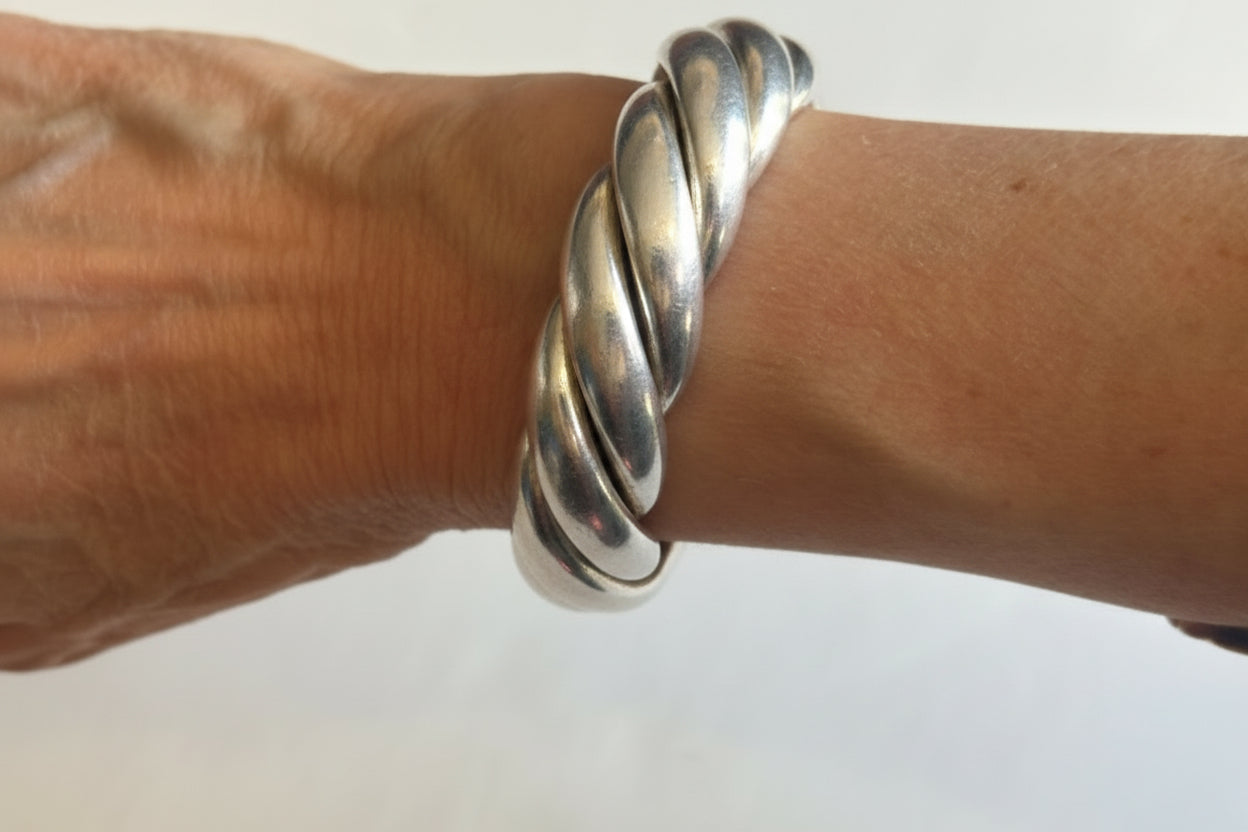 Silver bracelet on a wrist against a white background