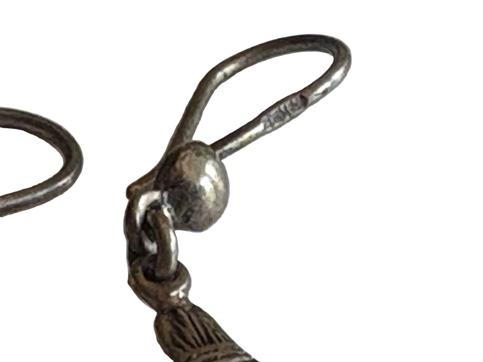 Close-up of a silver earring wire with hallmark on white background