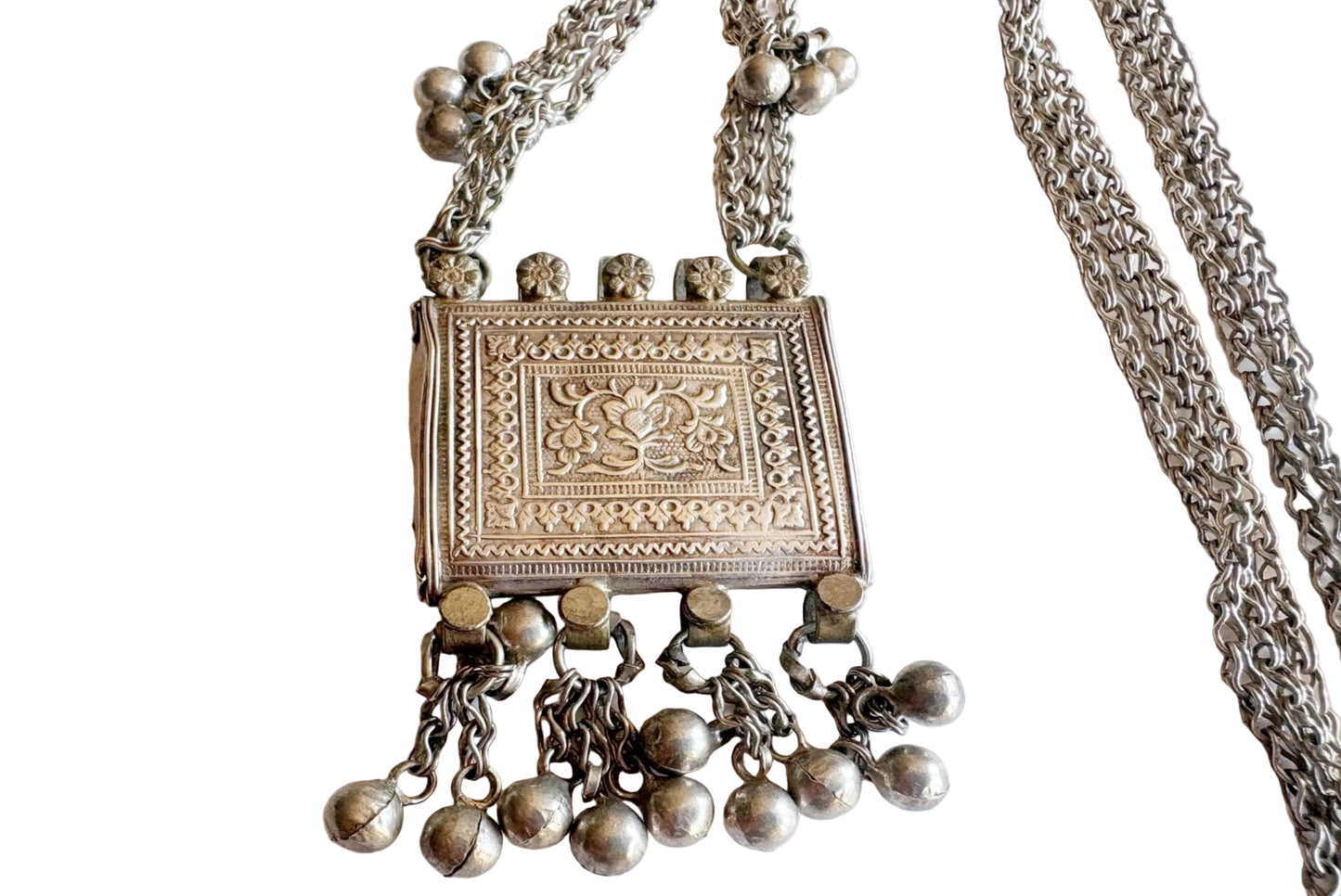 A silver necklace featuring an engraved rectangular pendant with dangling bell charms, displayed on a plain white background.