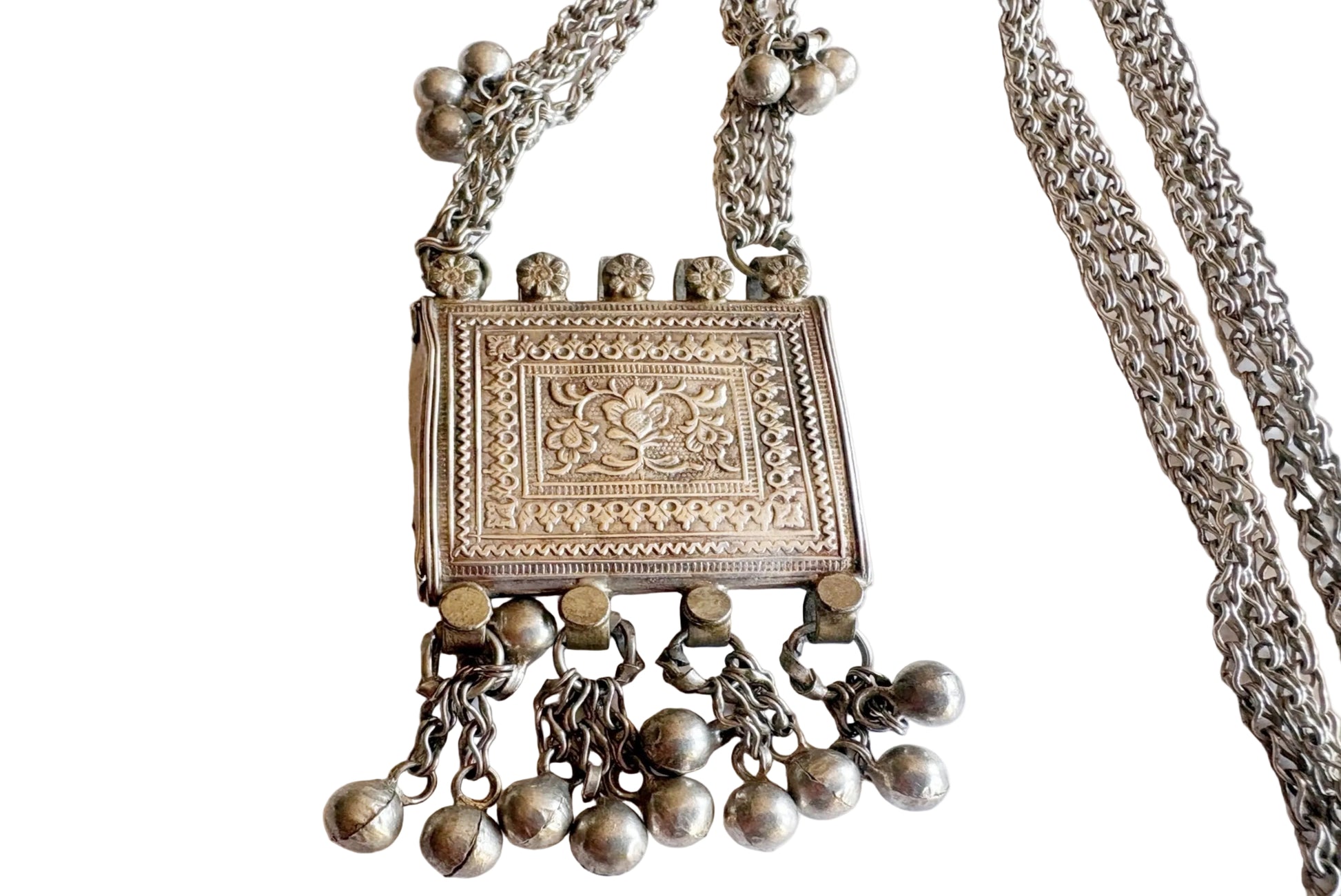 A silver necklace featuring an engraved rectangular pendant with dangling bell charms, displayed on a plain white background.