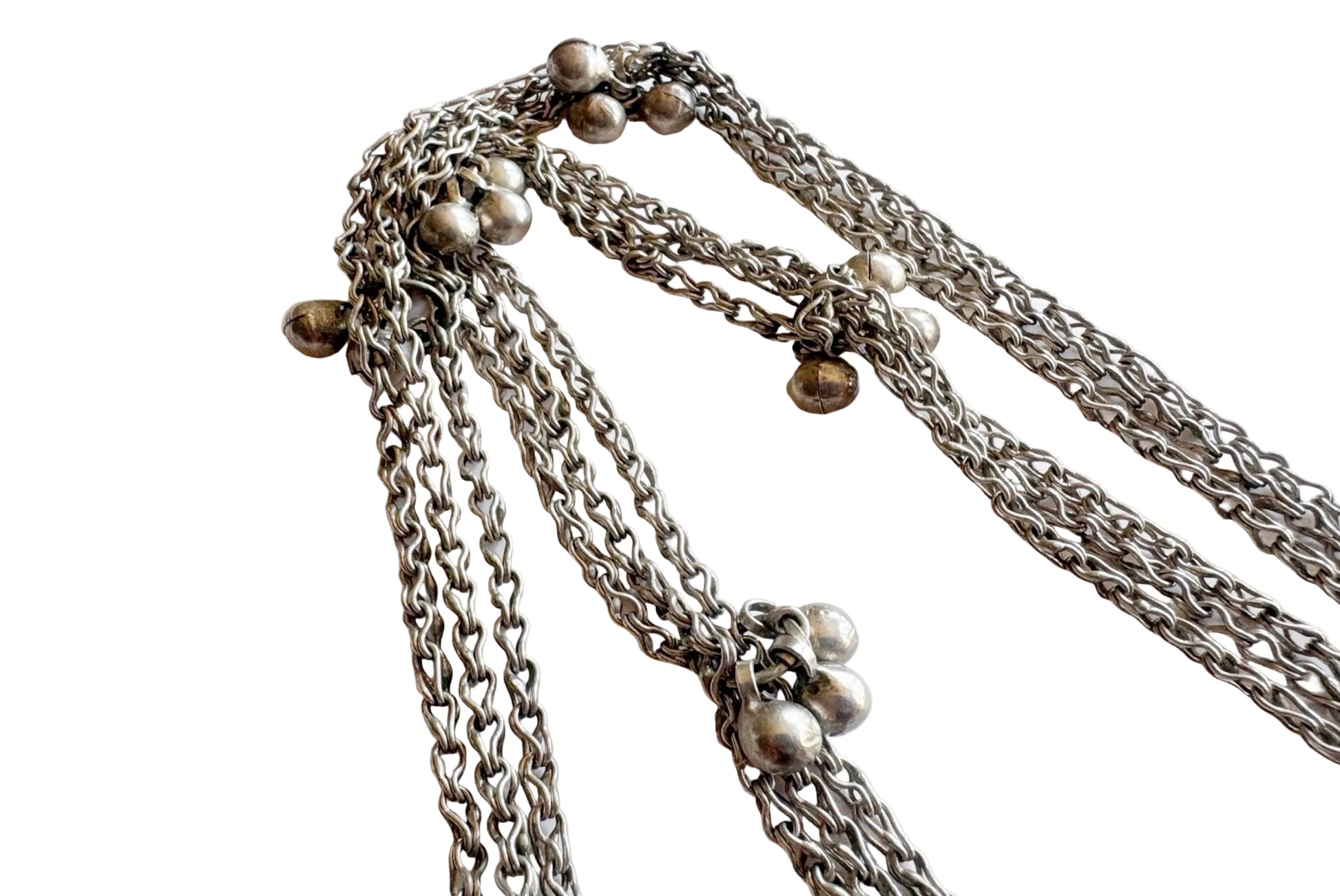 A close-up of a silver chain necklace with multiple draped chains and small silver bead details, photographed on a plain light background.