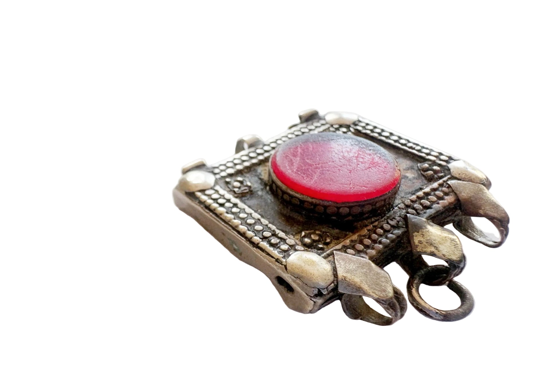 Decorative pendant with a red central gem and silver metalwork on a white background