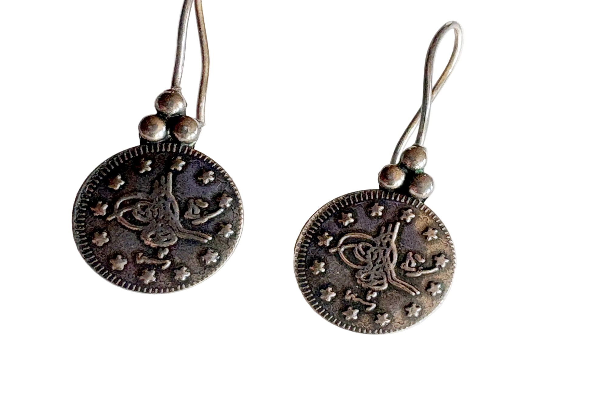 Pair of silver coin earrings on a white background