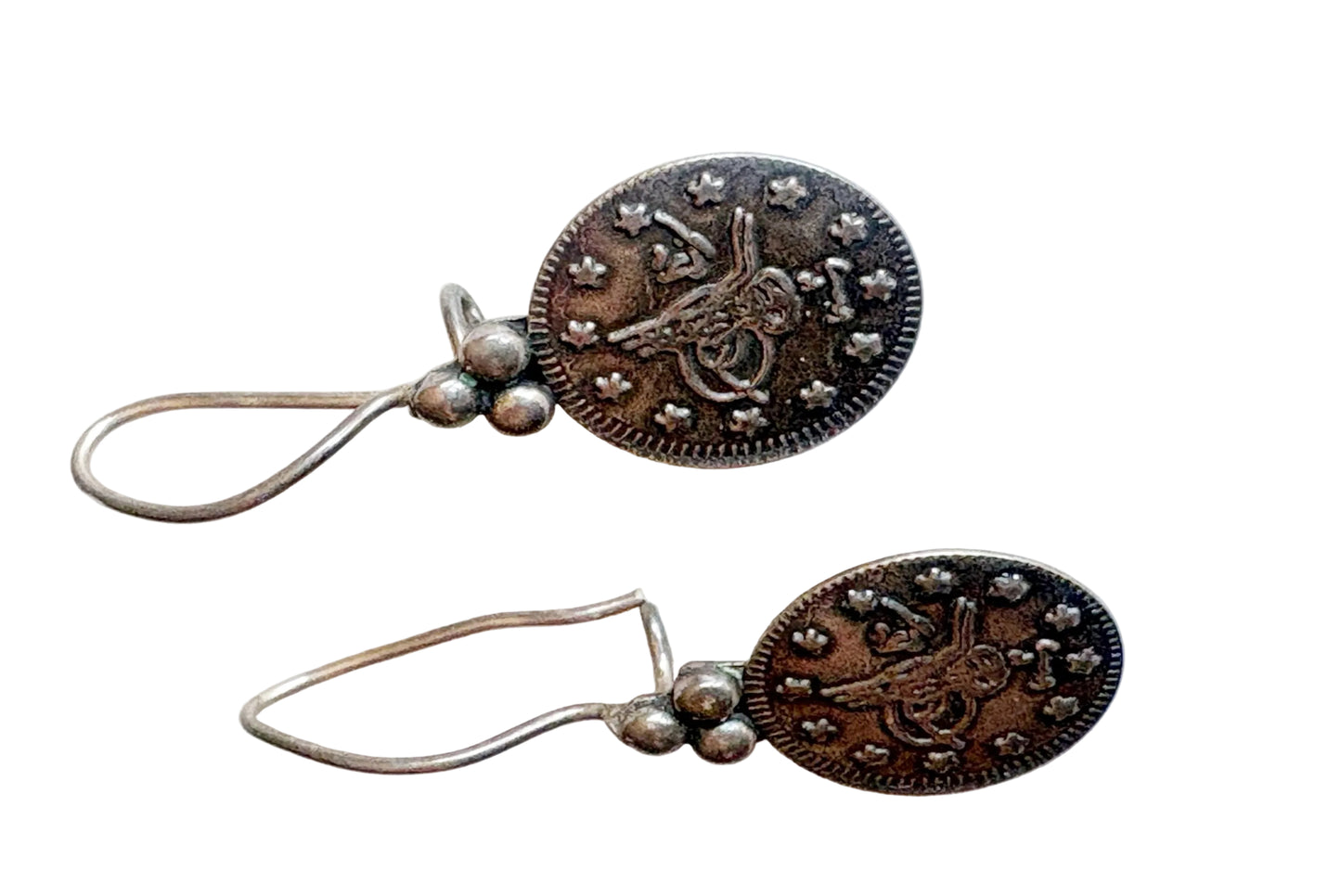 Pair of silver coin earrings on a white background