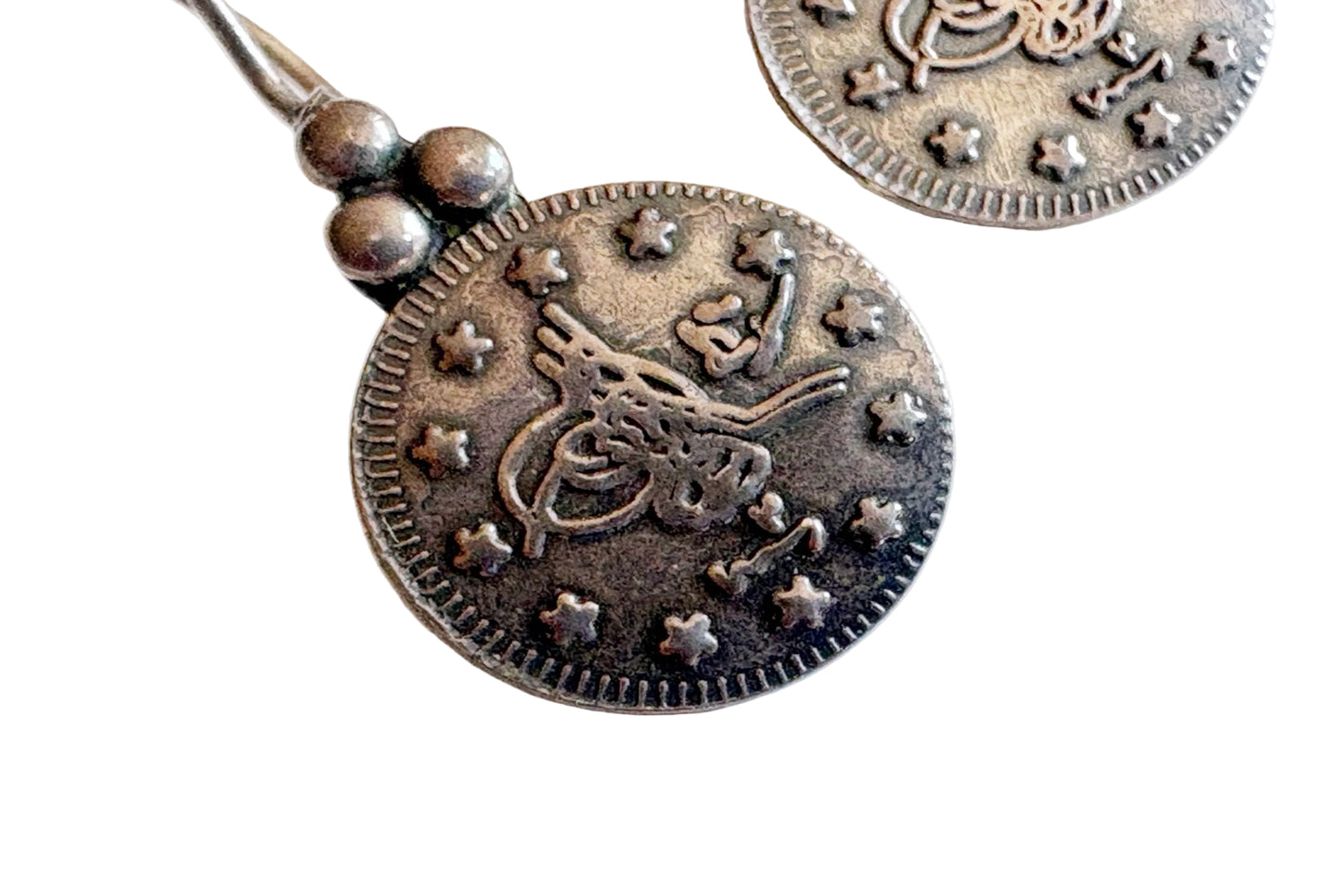 Silver coin-shaped pendant with star patterns on a white background