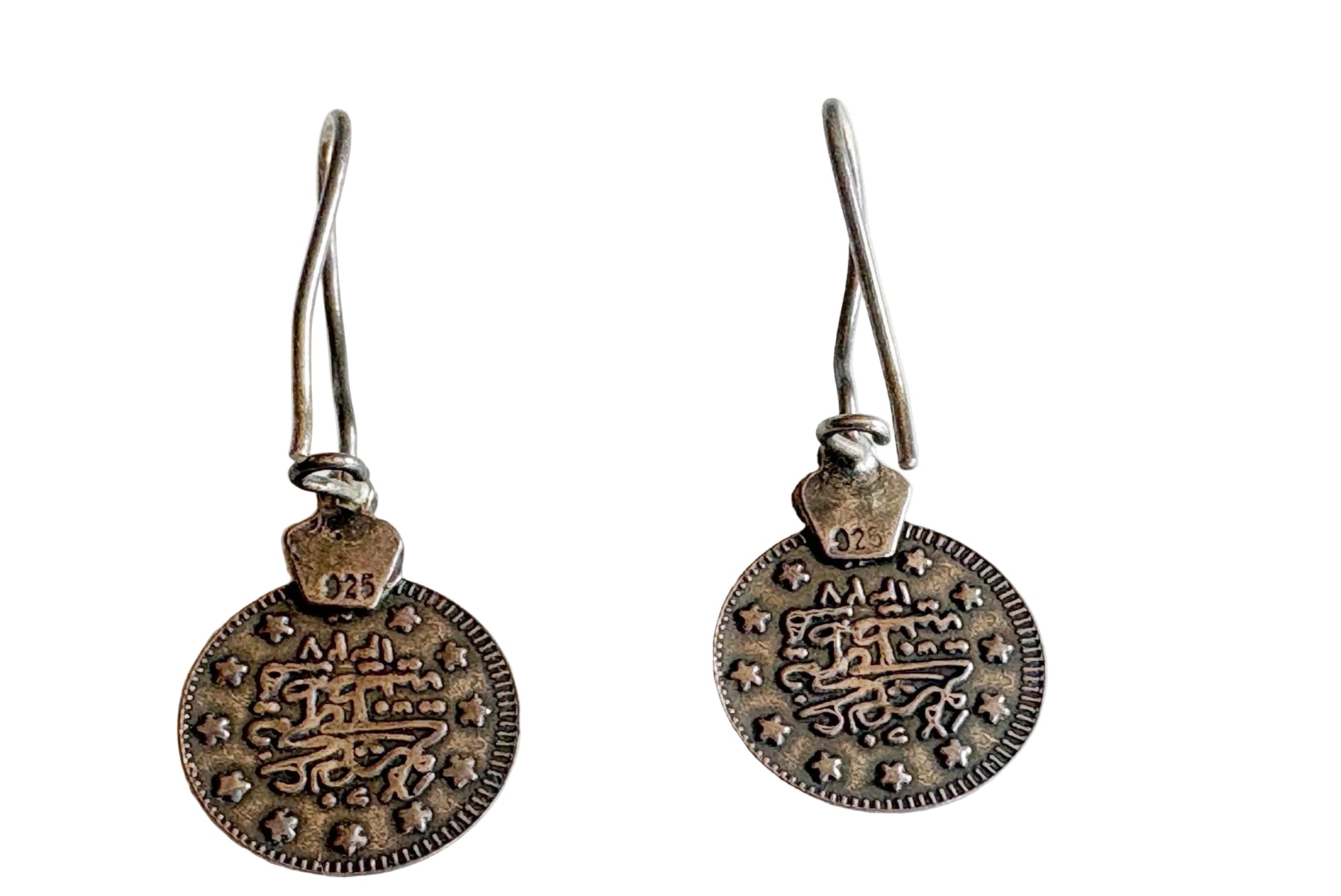 Pair of silver earrings with intricate designs on a white background