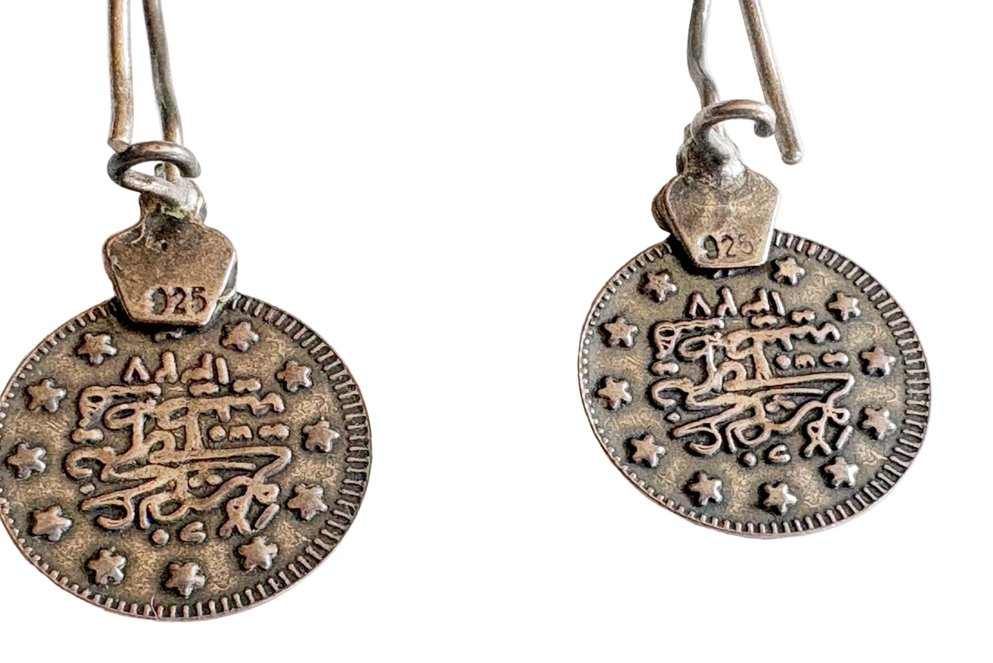 Pair of silver coin earrings on a white background