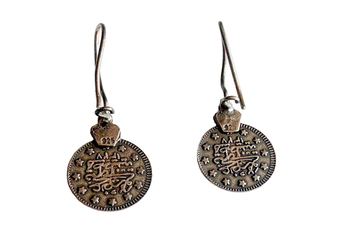 Pair of silver earrings with intricate designs on a white background