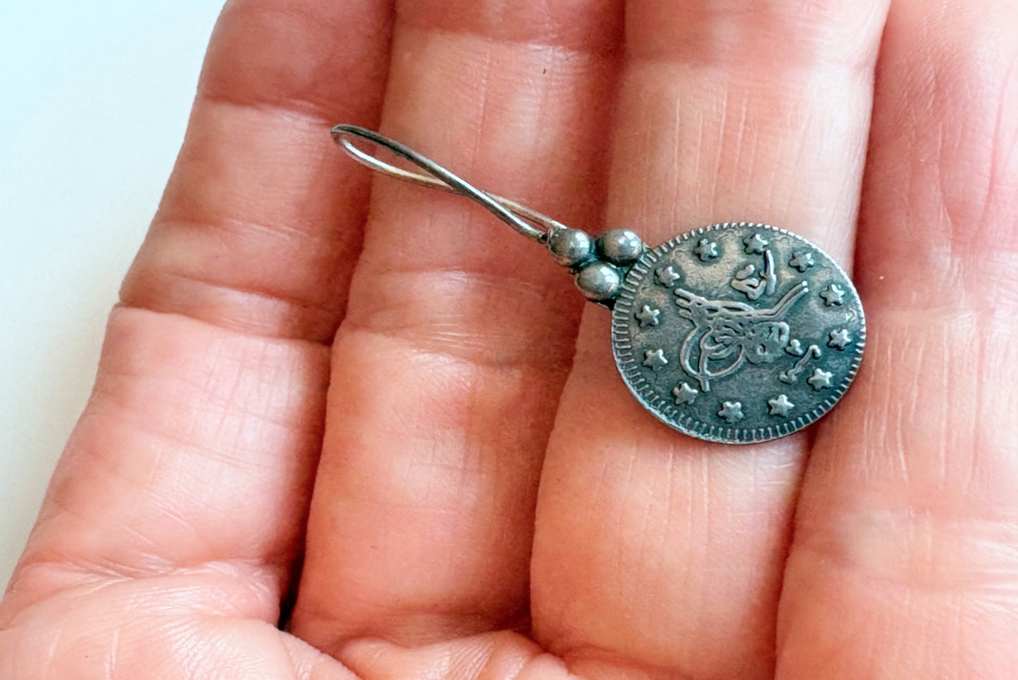 Silver earring with Ottoman coin held in hand