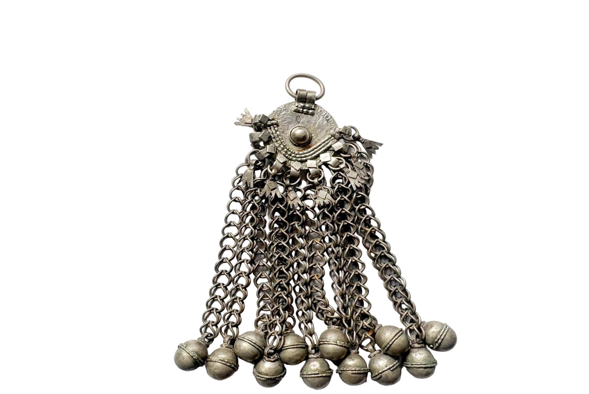 A vintage silver coin ornament with a decorative top cap, hanging chain links, and multiple small bell-shaped pendants at the bottom, shown on a plain white background.