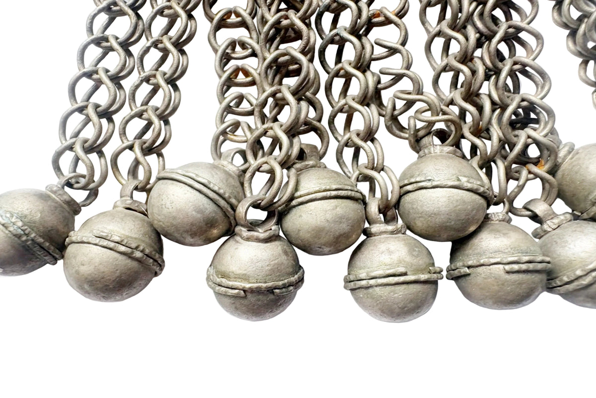 A close-up of a silver-toned metal chain  with multiple round bell-shaped charms, shown against a plain white background.