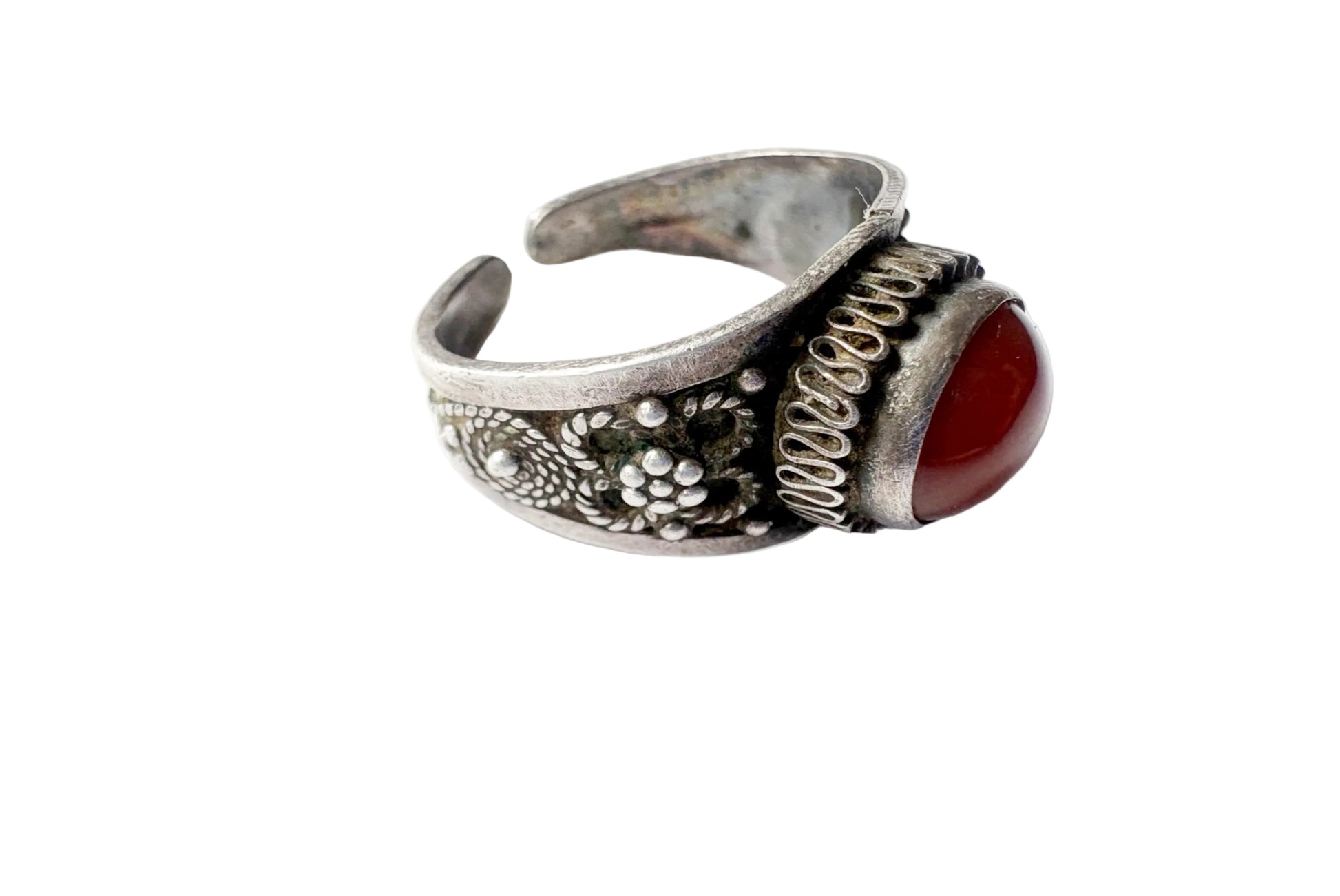 An antique-style silver cuff ring featuring a carved floral pattern, a textured spiral accent, and a polished red cabochon gemstone, shown on a white background.