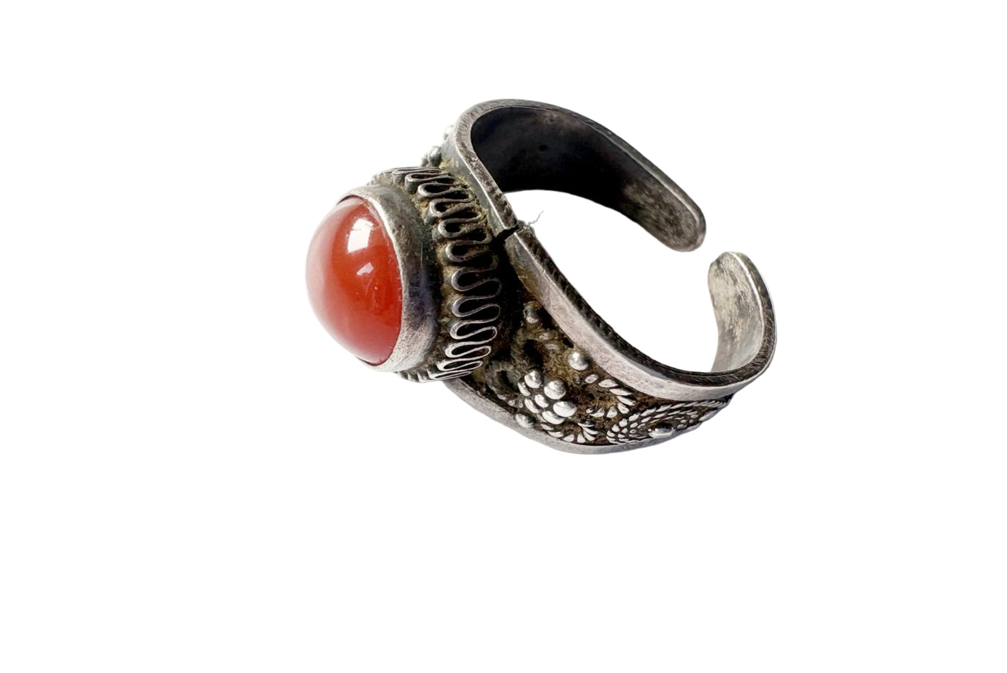An antique silver ring with a floral design and a round red cabochon gemstone, shown on a plain white background.