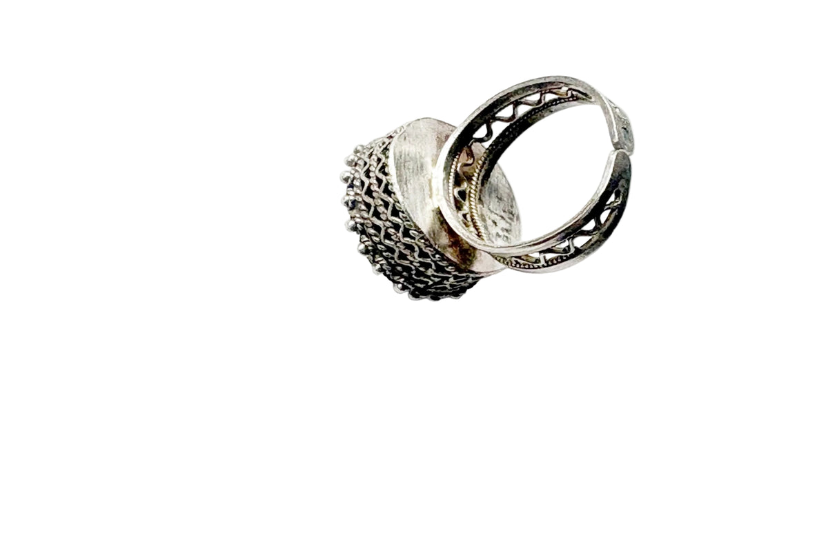 A silver ring with a textured, chain-like outer band and an openwork filigree inner band, photographed on a plain white background.