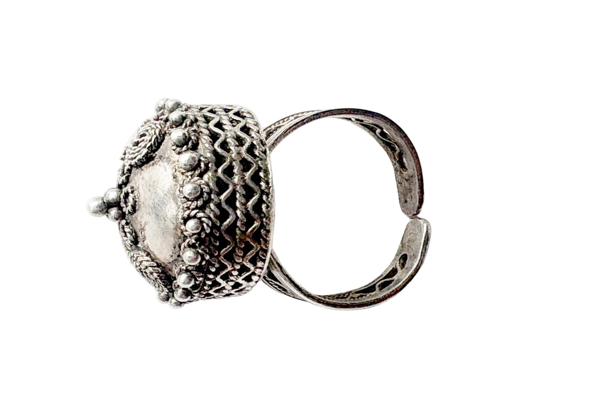 An ornate silver ring with a highly detailed, textured dome-shaped top featuring intricate filigree and beadwork, shown on a plain white background.