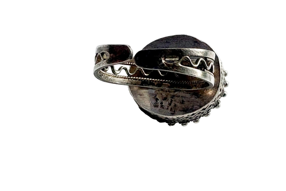 A handmade silver ring with intricate band shown on a light gray background.
