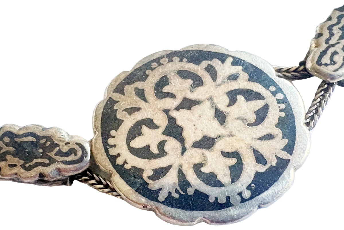 Silver and niello scalloped medallion on a white background