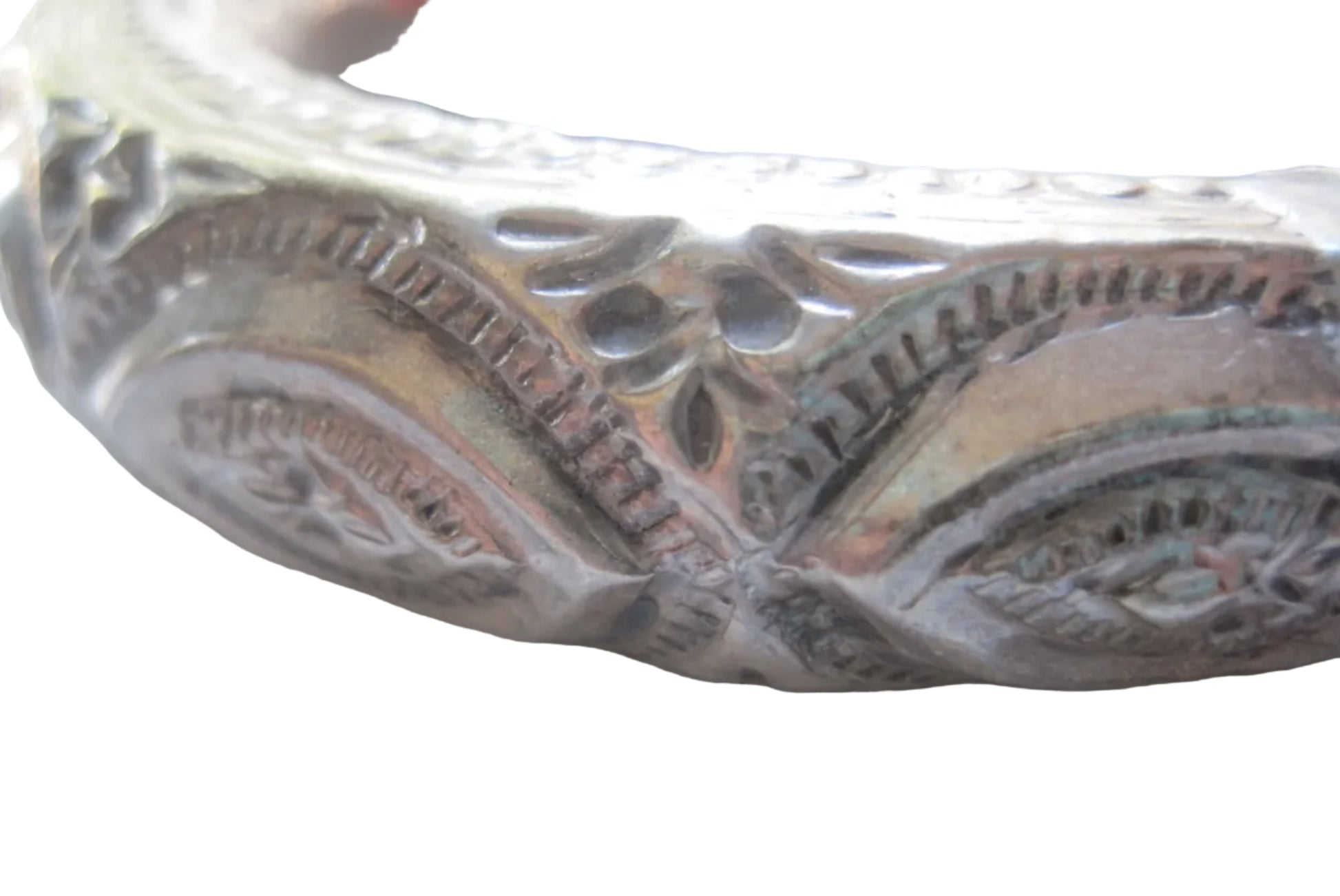 Close-up of an ornate silver-bangle with engraved floral and scrollwork details, showing a patina of silver tones.