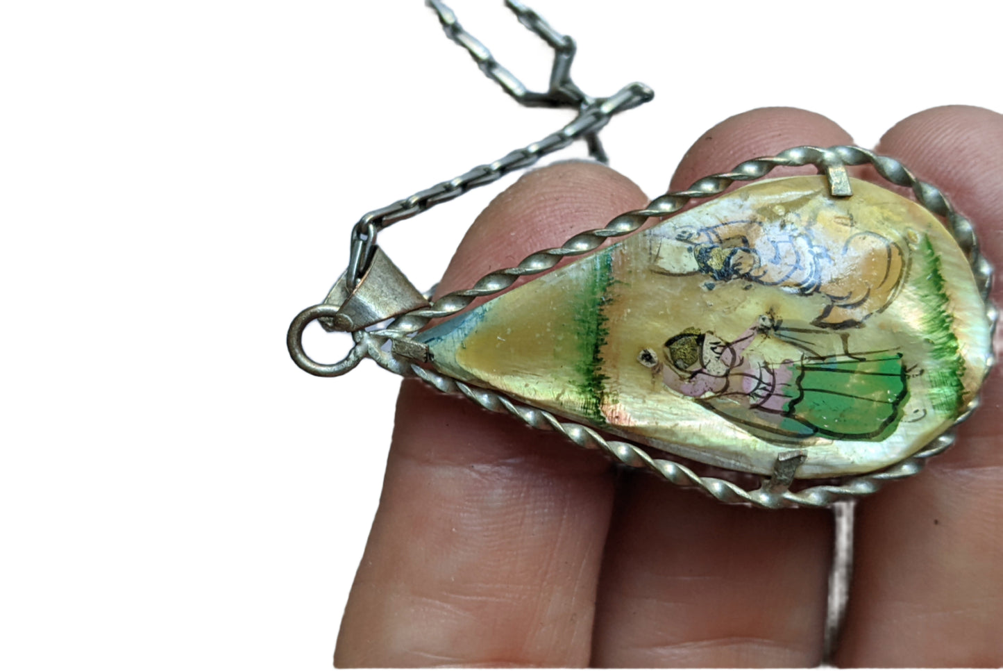 Teardrop-shaped pendant with hand-painted design held by a hand against a light background