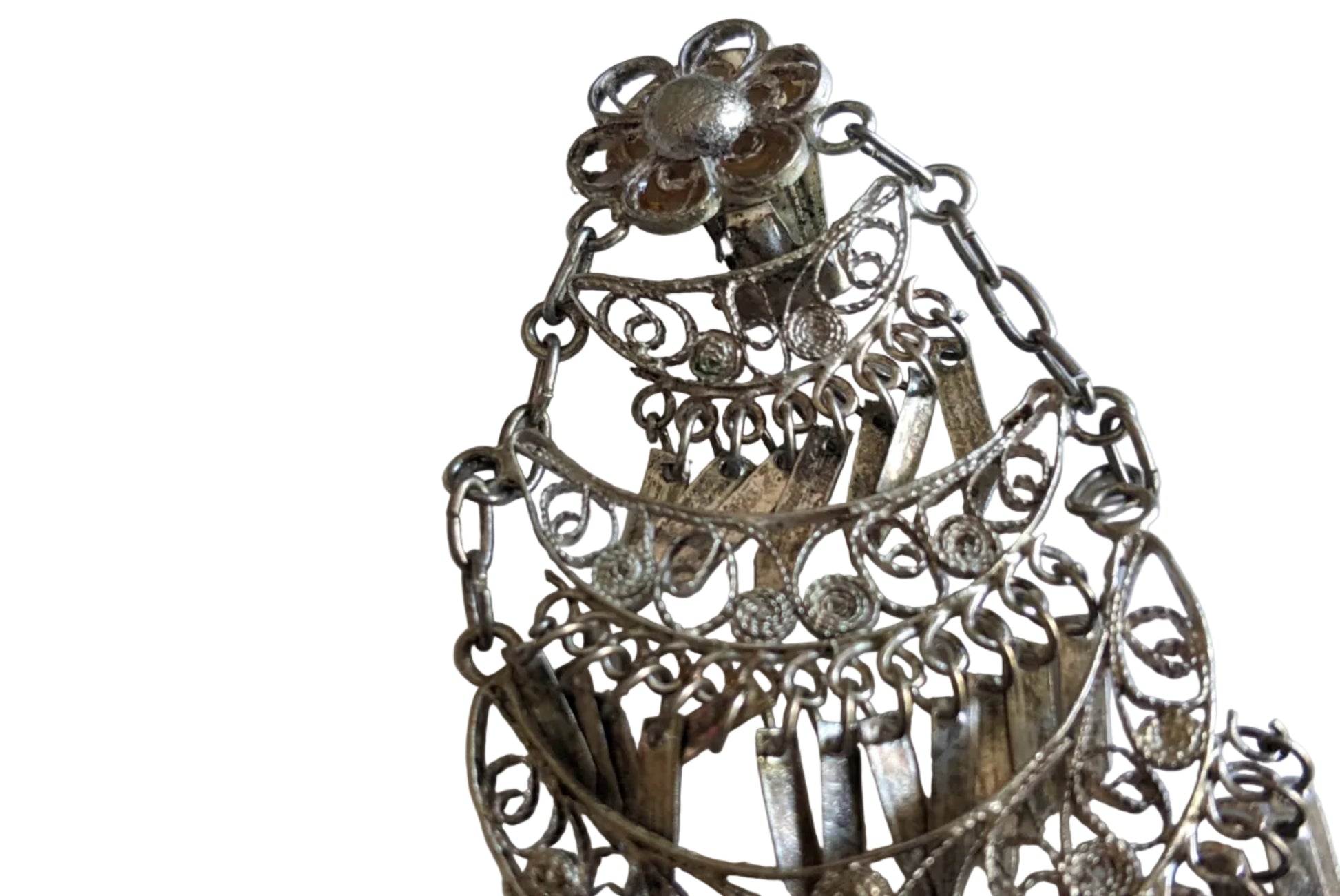 Close up of a filigree chandelier earring on a white background