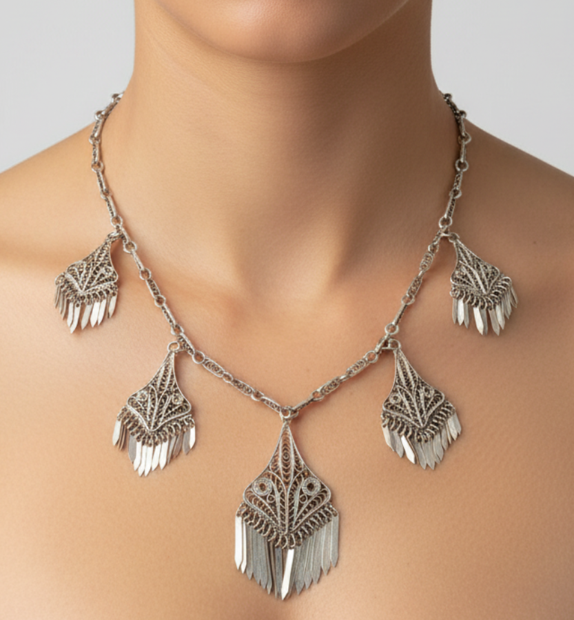 Silver necklace with dangling pendants worn by a model on a plain background