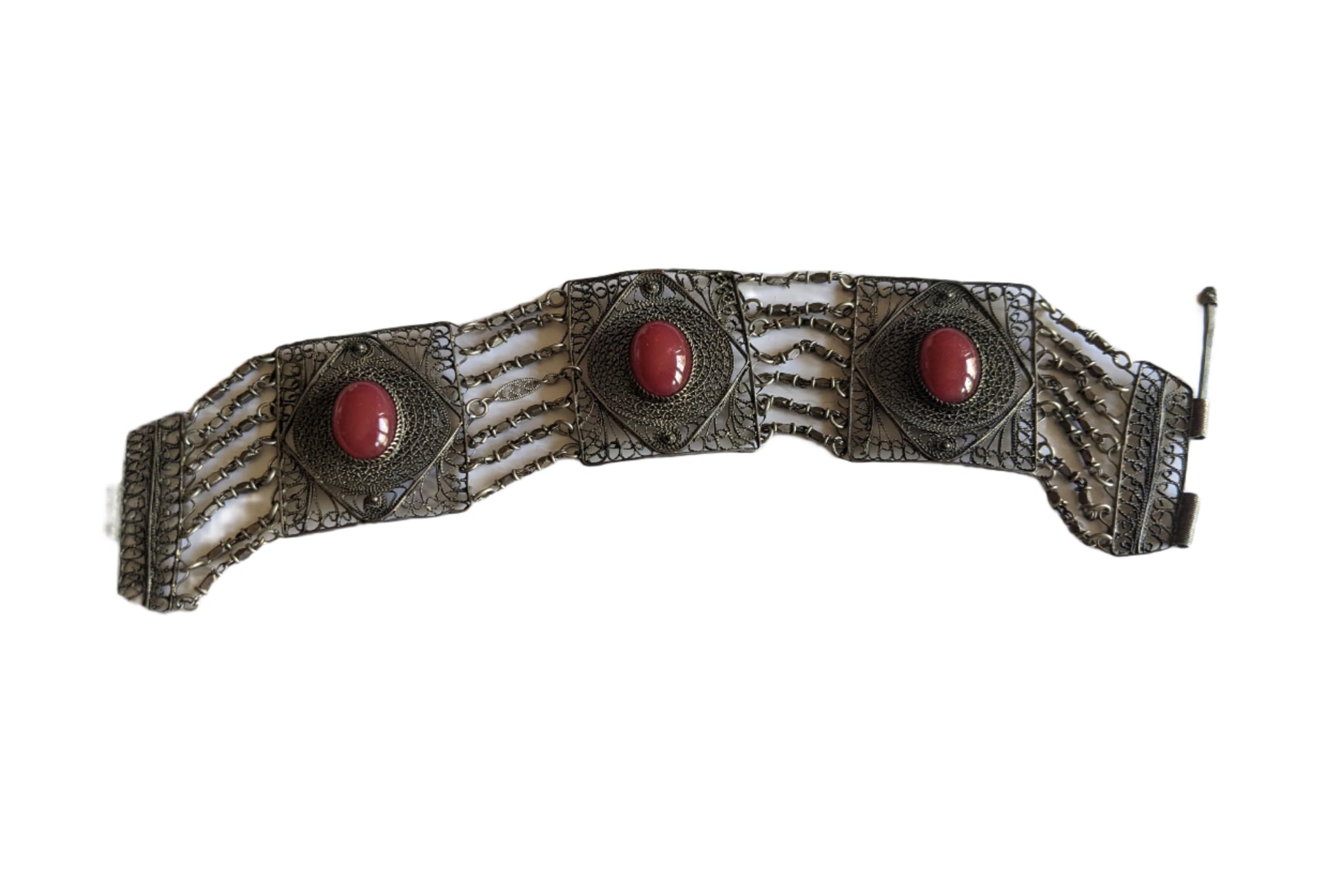 Filigree link bracelet with red stones and intricate filigree on a white background