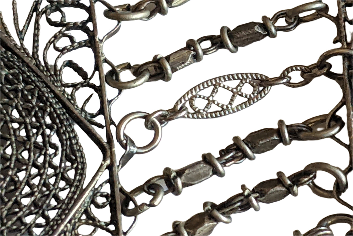 Close-up of a silver chain with intricate designs on a white background