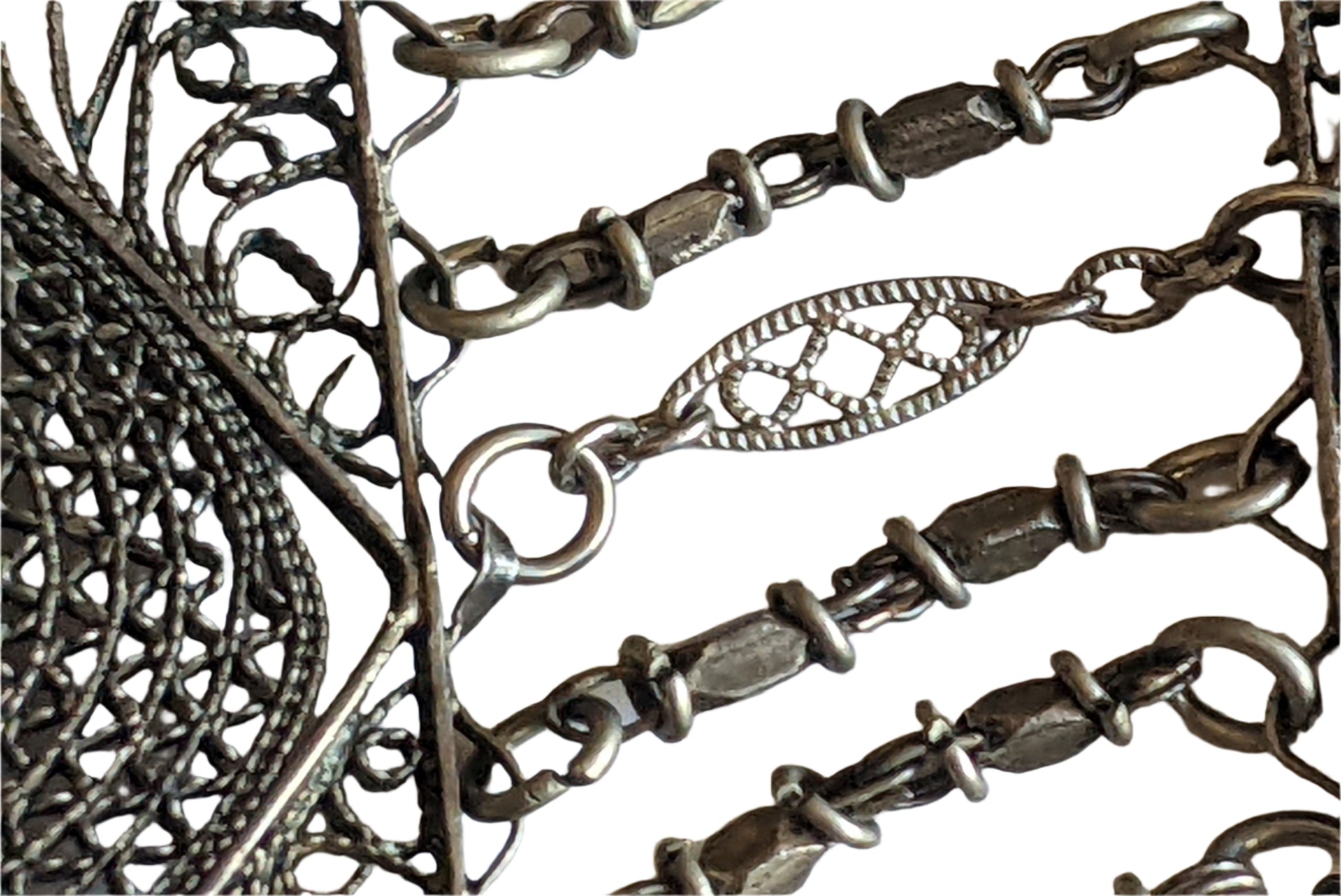 Close-up of a silver chain with intricate designs on a white background